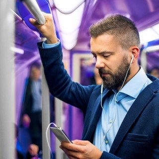 Image of man holding phone with earphones in a train